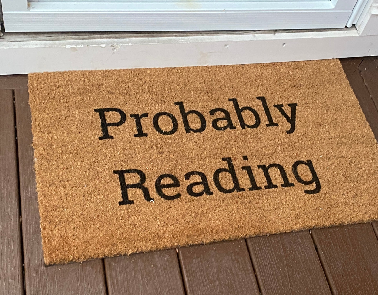 Doormat with 'Probably Reading' text on a wooden floor.