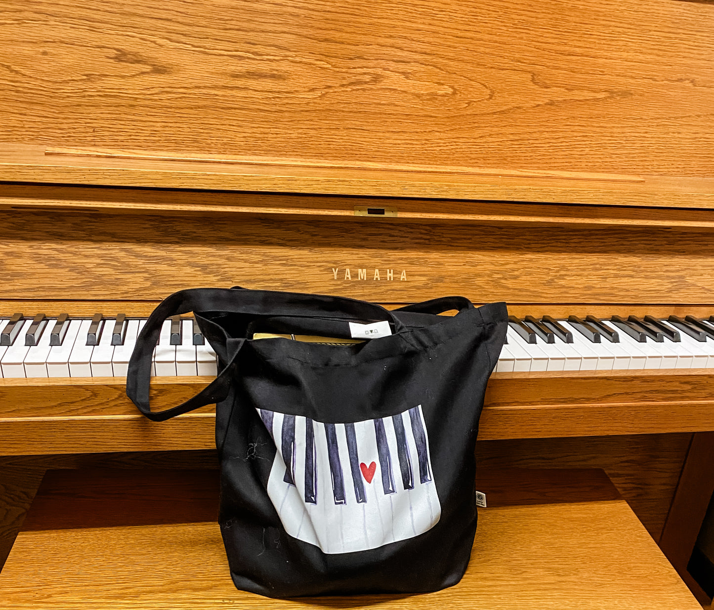 Black tote bag with a watercolor piano keyboard graphic 